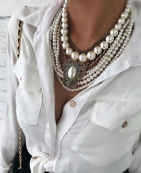 Woman in white shirt wearing multiple pearl necklaces